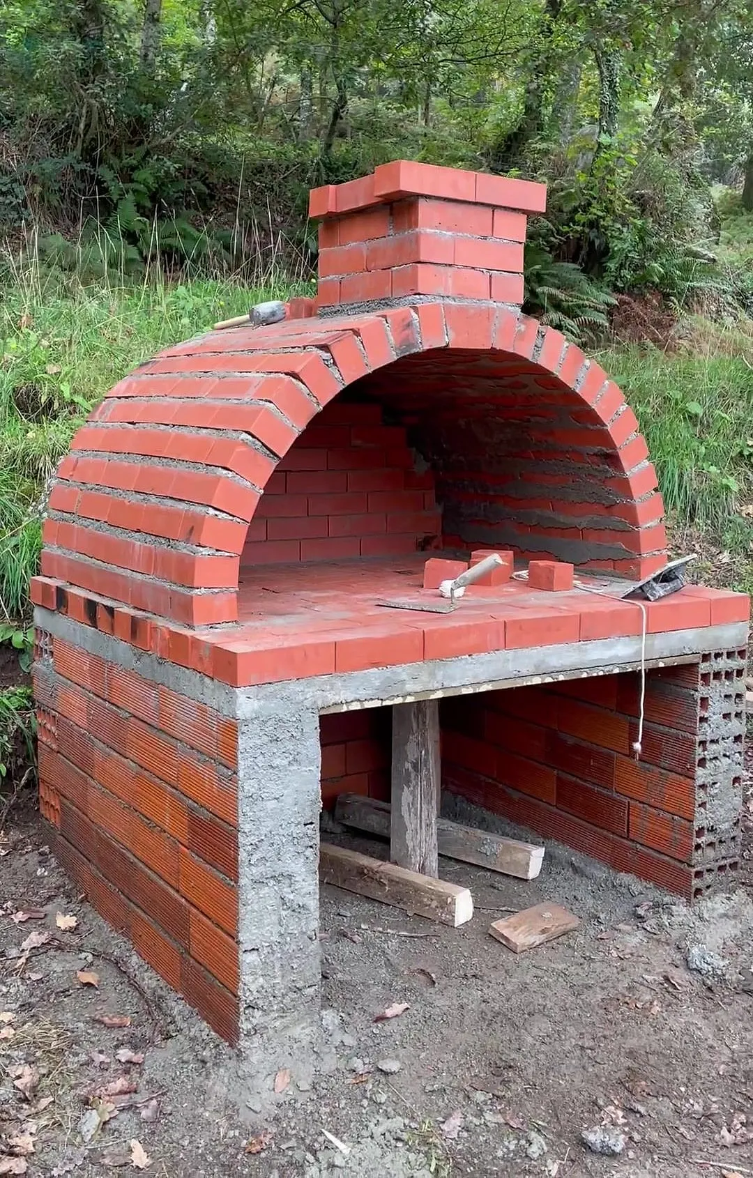 The brick wood-fired pizza oven Shahin built, with a chimney, on a concrete and brick base
