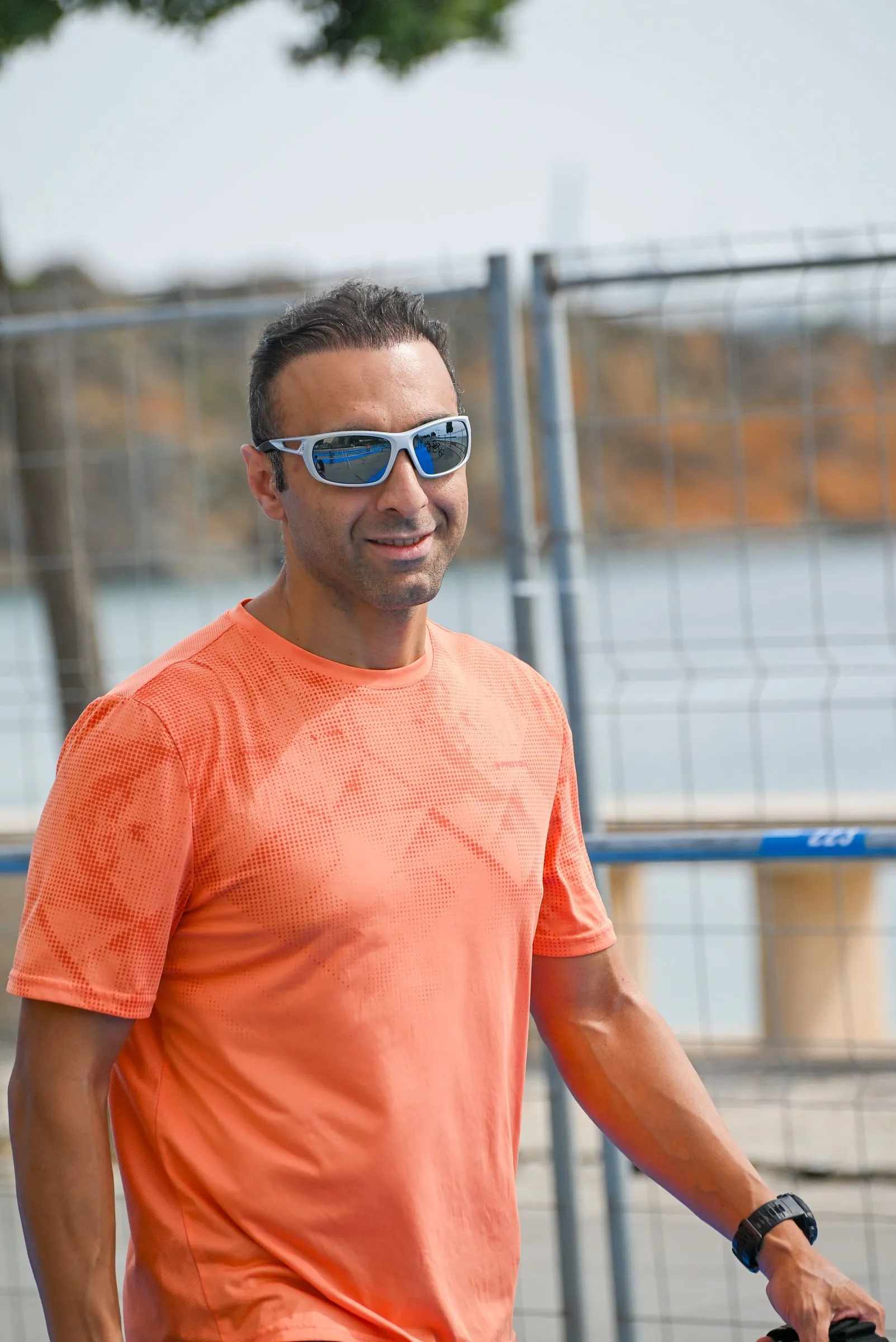 Shahin in an orange t-shirt and sunglasses, smiling